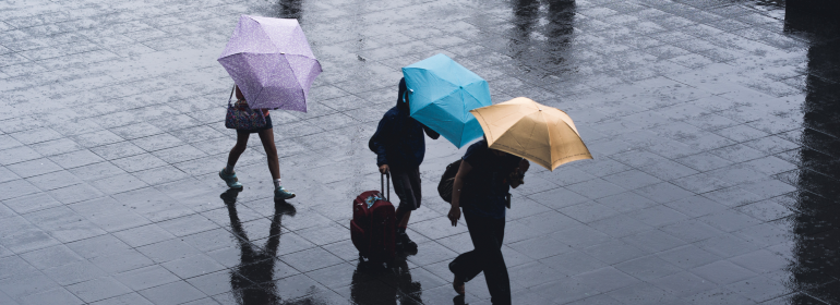 Coping with events outside your control - three people with umbrellas in rain